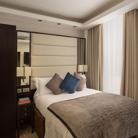 מלון לונדון Montcalm Brewery Townhouse מראה חיצוני תמונה The image shows a cozy bedroom. It features a comfortable double bed with a light-colored duvet and decorative pillows in shades of blue and gray. The headboard is upholstered in a soft material, and there are bedside lamps on either side of the bed.