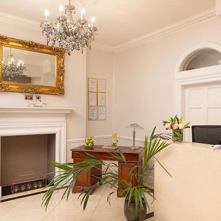 מלון לונדון Montcalm Brewery Townhouse מראה חיצוני תמונה The photo shows a stylish reception area. There is a decorative chandelier hanging from the ceiling, providing elegant lighting. A large, ornate mirror is mounted on the wall beside the fireplace, which features a simple, classic design. In front of 