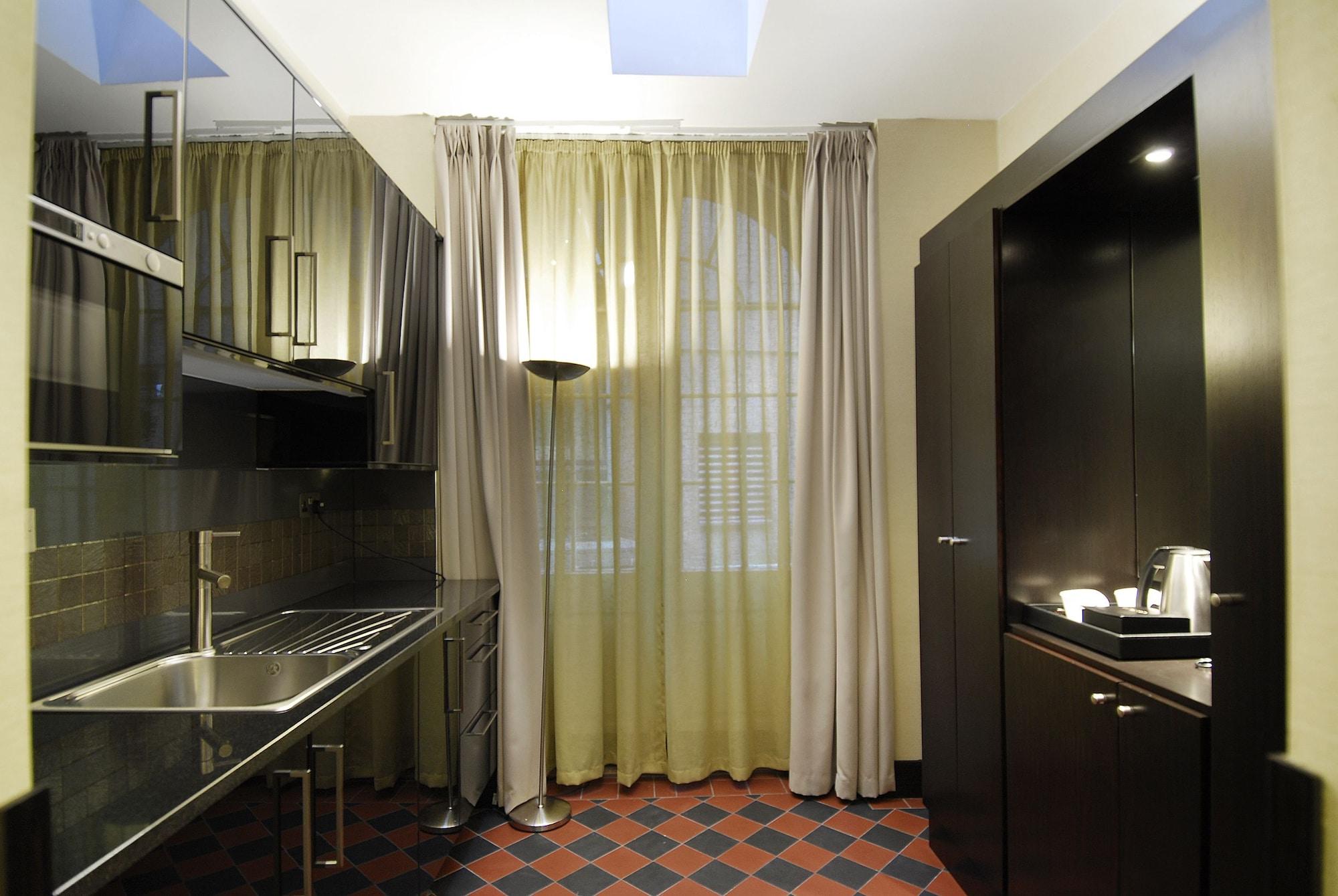 מלון לונדון Montcalm Brewery Townhouse מראה חיצוני תמונה The photo shows a modern kitchen space. On the left side, there is a sleek countertop and kitchen cabinets in a dark finish. The backsplash appears shiny, reflecting the surroundings. To the right, there is a tall black cabinet. A window is covered w