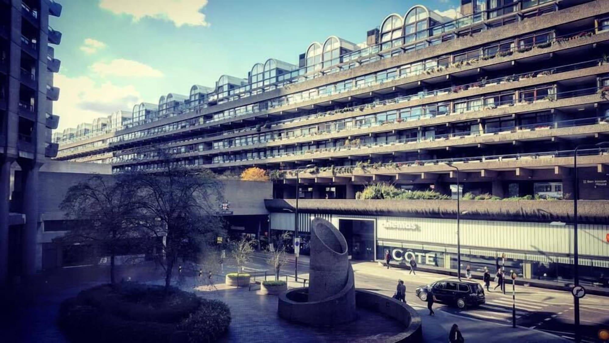 מלון לונדון Montcalm Brewery Townhouse מראה חיצוני תמונה The photo shows a modern architectural structure with multiple levels, featuring a series of large, rectangular balconies. Below this building, there is a plaza or courtyard area with a sculptural piece, which appears to be made of stone. Surrounding