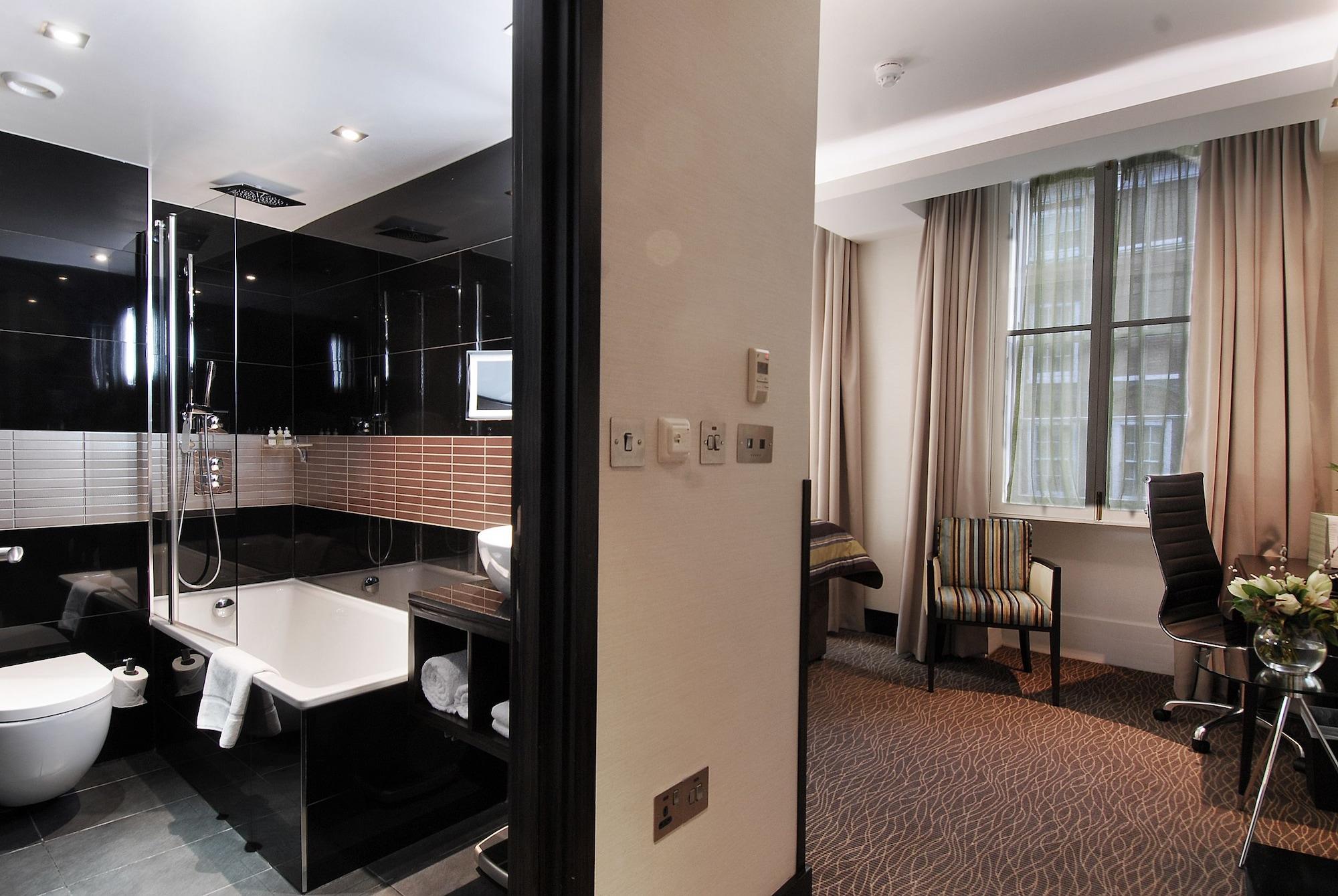 מלון לונדון Montcalm Brewery Townhouse מראה חיצוני תמונה The photo shows a modern hotel room that features an elegant bathroom on one side and a living area on the other. 

1. **Bathroom**: The bathroom is stylishly designed with a combination of black and white tiles. It includes a bathtub, a shower area 