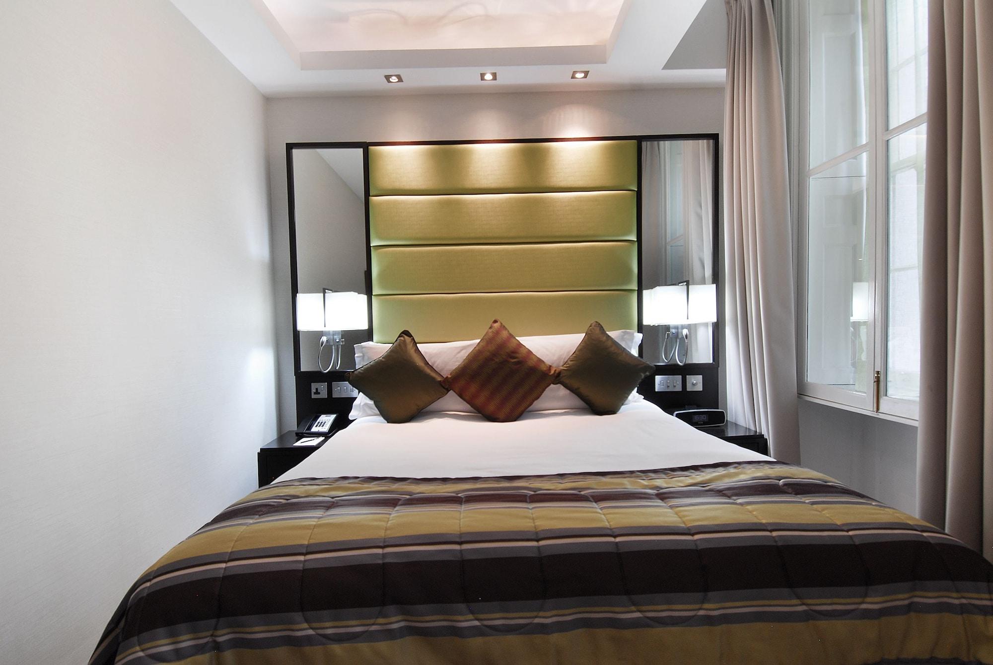 מלון לונדון Montcalm Brewery Townhouse מראה חיצוני תמונה The photo shows a stylishly decorated bedroom. The bed is centered in the room, featuring a white comforter with a plaid pattern in shades of brown and green. There are three decorative pillows on the bed, two in shades of brown and one in dark green