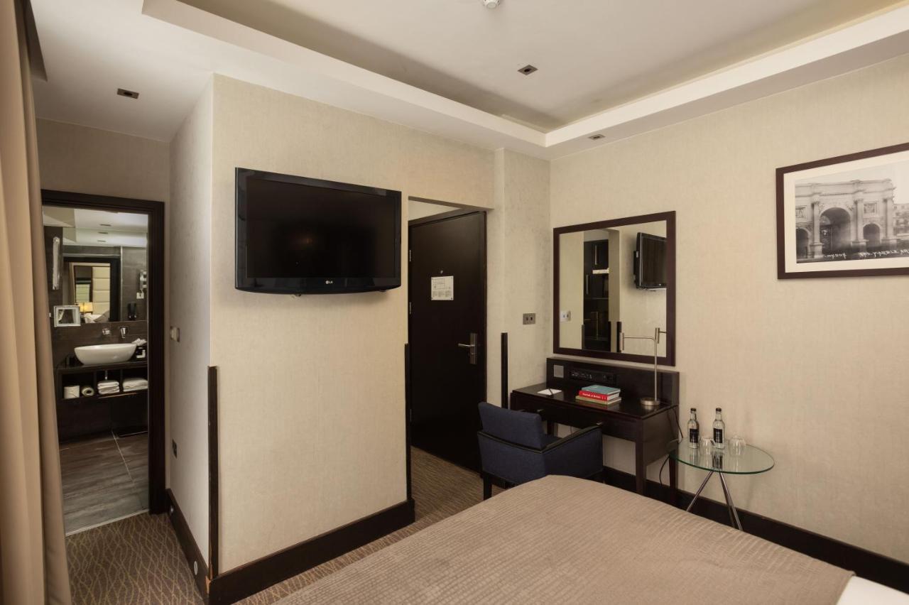 מלון לונדון Montcalm Brewery Townhouse מראה חיצוני תמונה The photo shows a hotel room featuring a double bed with a neutral-colored bedspread. On one wall, there is a flat-screen TV mounted. Adjacent to the bed, there is a stylish desk with a chair and a small glass table. A mirror is positioned above the 