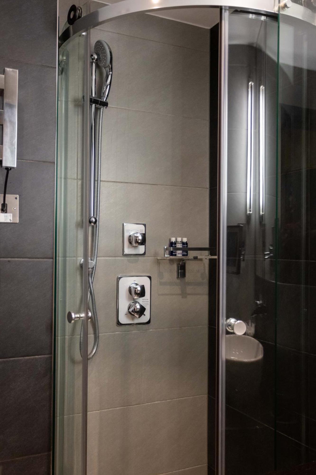 מלון לונדון Montcalm Brewery Townhouse מראה חיצוני תמונה The photo shows a modern shower area. It features glass panels and tiled walls in a neutral color palette, creating a sleek and contemporary look. There are two main control panels for adjusting the water temperature and pressure, with various knobs 