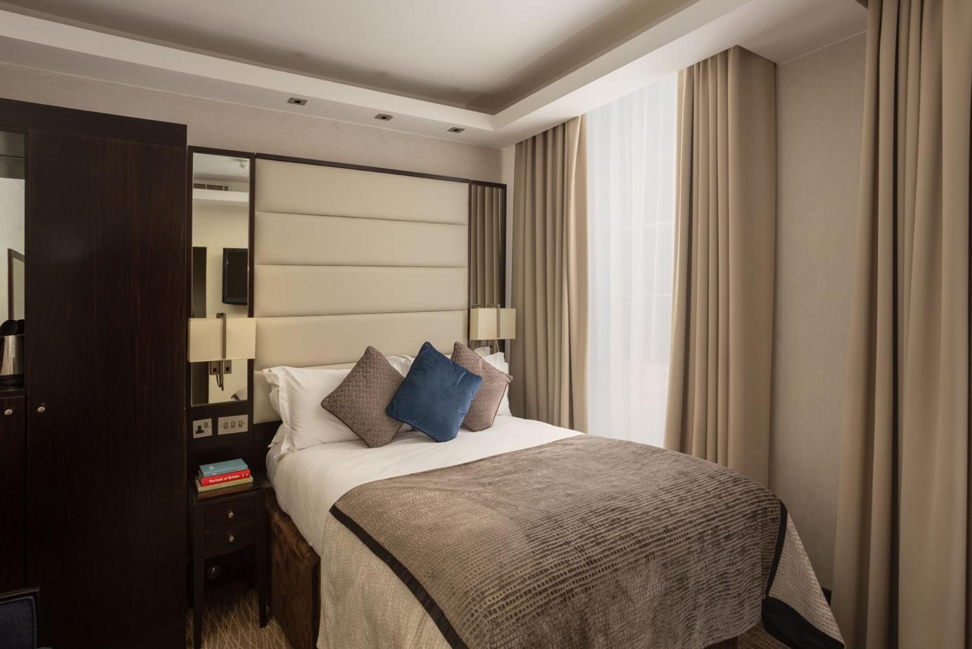 מלון לונדון Montcalm Brewery Townhouse מראה חיצוני תמונה The photo shows a modern hotel room with a cozy design. It features a double bed with a light-colored headboard and a soft, stylish blanket. There are decorative pillows on the bed, including a blue one. On either side of the bed, there are small nig