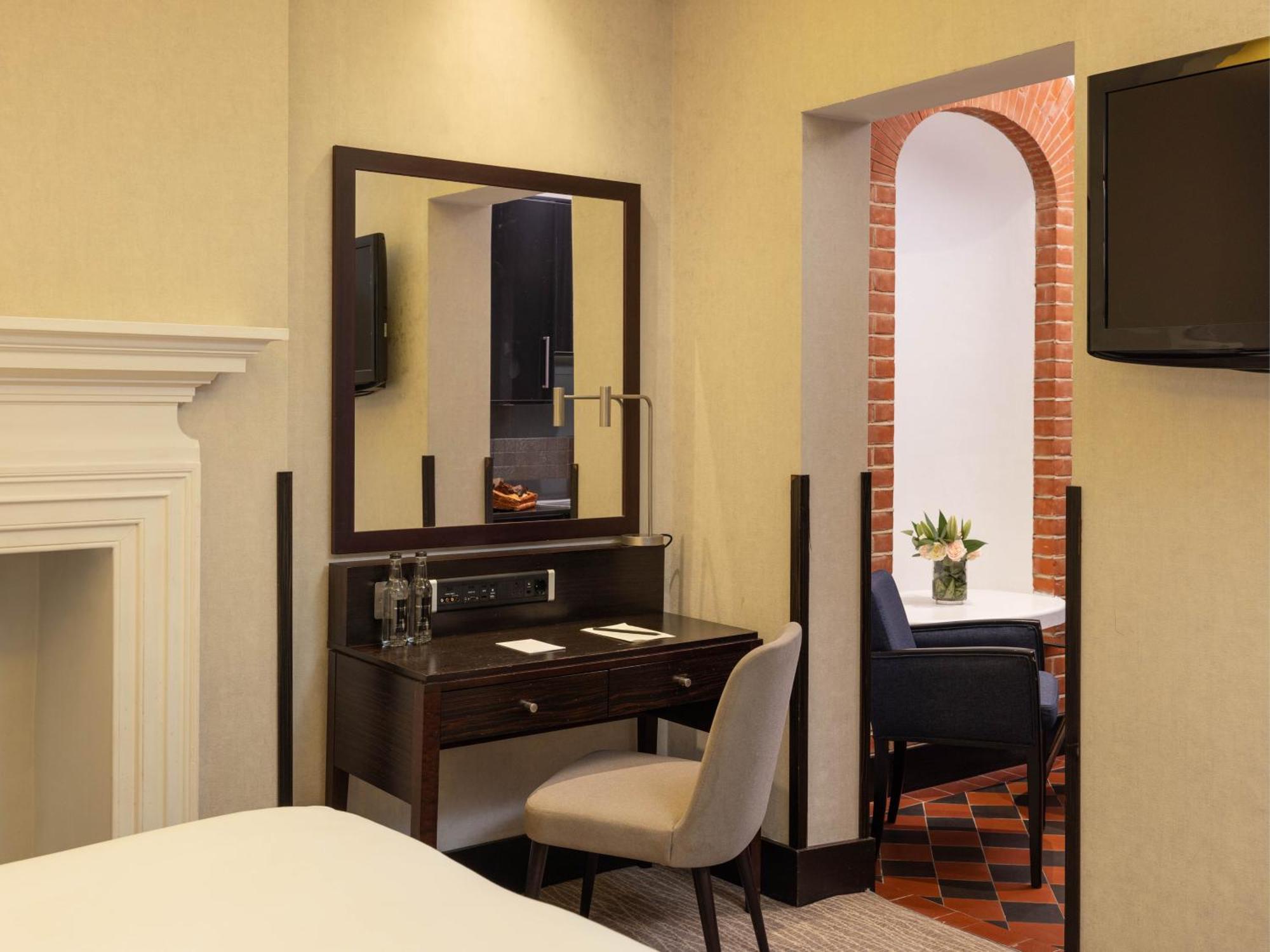 מלון לונדון Montcalm Brewery Townhouse מראה חיצוני תמונה The photo displays a hotel room setup. On the left side, there's a bed with a simple white bedding arrangement. Adjacent to the bed, there's a wooden desk with a chair, along with a mirror above the desk. The desk area is equipped with some glassware