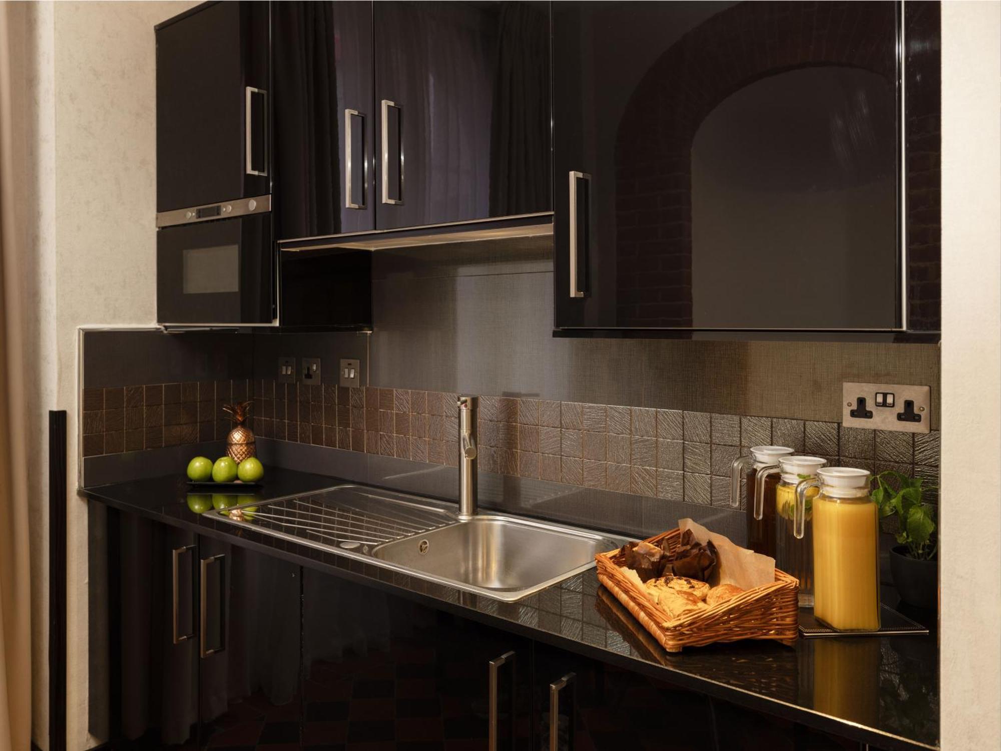 מלון לונדון Montcalm Brewery Townhouse מראה חיצוני תמונה The photo shows a modern kitchen with sleek black cabinetry and a glossy finish. The kitchen features a stainless steel sink with a contemporary faucet, set against a dark, textured countertop. Above the counter, there are cabinets that match the cou