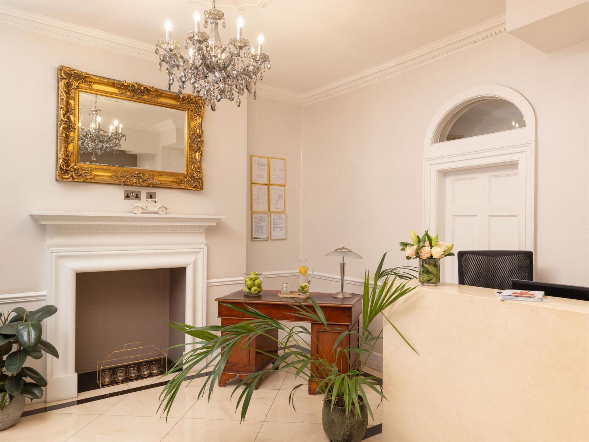מלון לונדון Montcalm Brewery Townhouse מראה חיצוני תמונה The photo shows a stylish reception area. There is a decorative chandelier hanging from the ceiling, providing elegant lighting. A large, ornate mirror is mounted on the wall beside the fireplace, which features a simple, classic design. In front of 