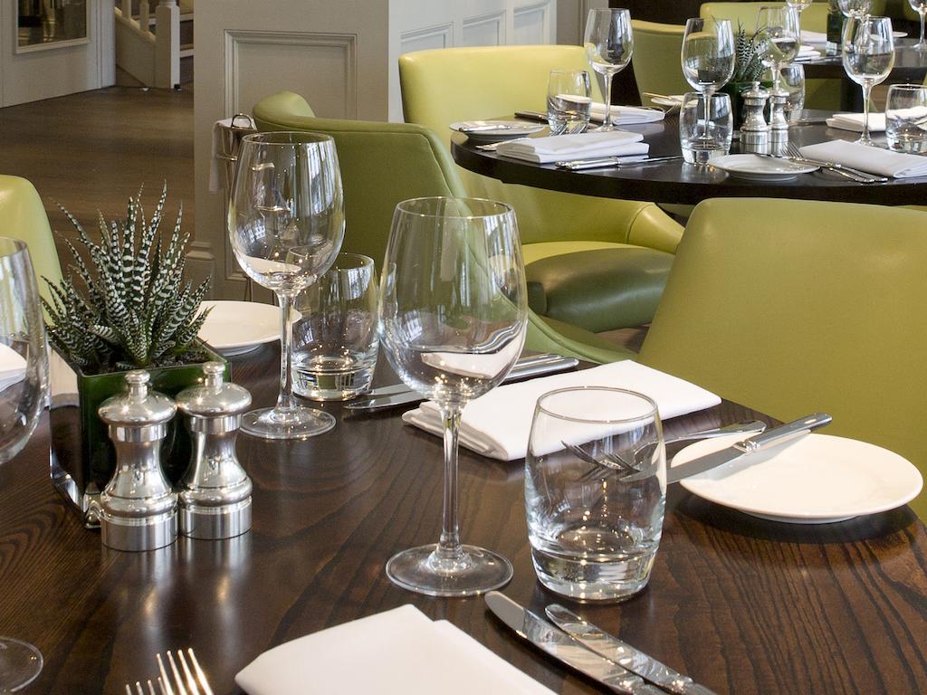 מלון לונדון Montcalm Brewery Townhouse מראה חיצוני תמונה The photo shows a dining setup in a restaurant. There are tables with a polished wooden surface and elegant place settings. Each setting includes multiple wine glasses and water glasses, neatly arranged with folded napkins. 

In the center, there are