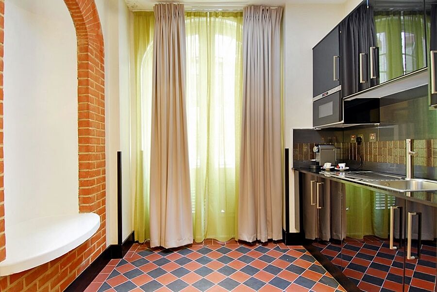 מלון לונדון Montcalm Brewery Townhouse מראה חיצוני תמונה The photo shows a kitchen area with modern design elements. There are large, light-colored curtains hanging from the windows, allowing natural light to filter in. The walls are partially exposed brick, giving a warm texture to the room. The flooring 