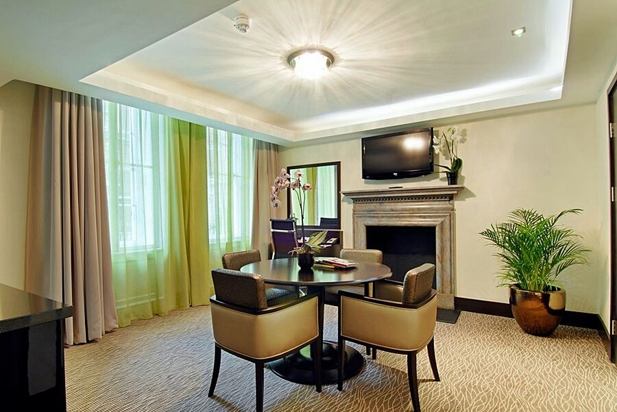 מלון לונדון Montcalm Brewery Townhouse מראה חיצוני תמונה The photo shows a well-furnished room, likely a hotel suite or a modern living space. It features a round dining table with four comfortable chairs. The walls are adorned with light-colored decor, and there are large windows with sheer and solid curt